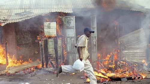 A member of the Luo tribe runs away from police and past a house reportedly owned by a Kikuyu which they ransacked and set ablaze by other members of his tribe during ethnic clashes in the central Kenyan town of Nakuru. (ROBERTO SCHMIDT, AFP/Getty Images)